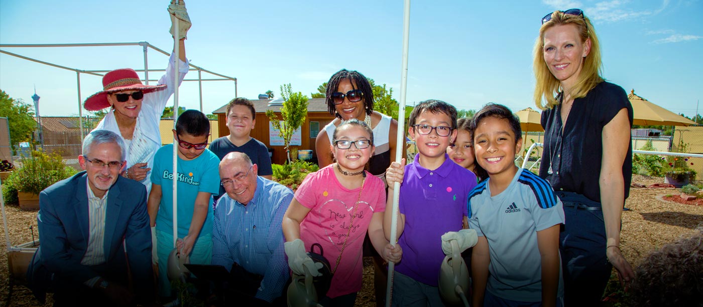 Foundation board members helping children plant flowers in garden